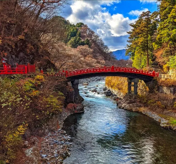 The red lacquered Shinkyo Sacred Bridge arching over the river in Nikko